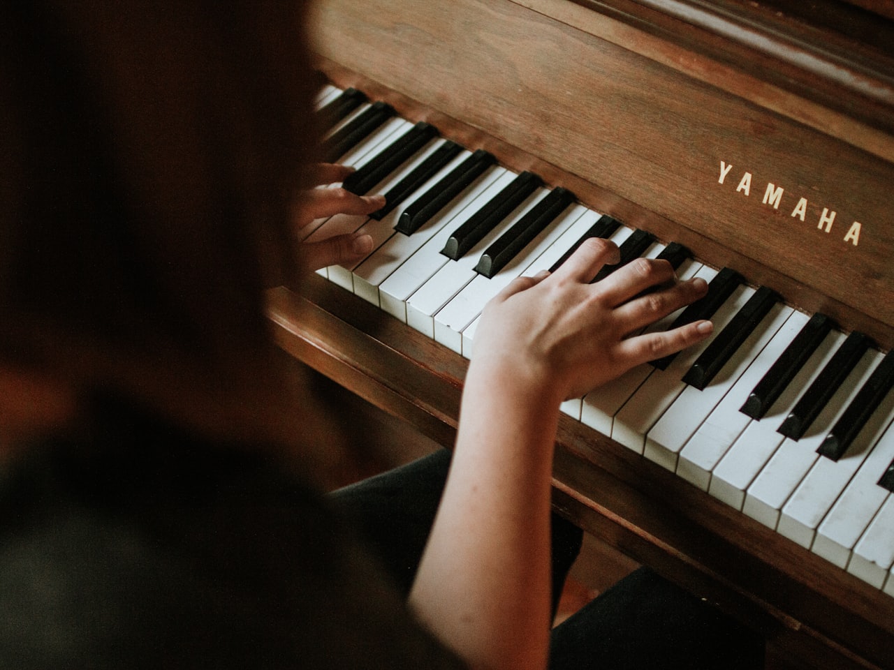 A teacher sitting beside a young student at a grand piano during a lesson